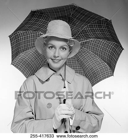 Stock Image - Studio portrait of young woman holding umbrella. Fotosearch