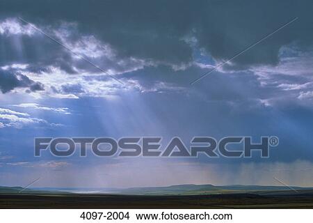 Picture - Sunbeam passing through storm clouds over a landscape, Alberta, Canada. Fotosearch