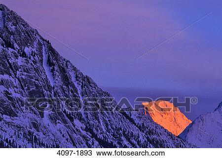 Stock Image - Sunlight falling over mountain peak, Colin Range, Jasper National Park, Alberta, Canada. Fotosearch