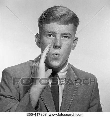 Stock Photo - Teenage boy whispering, studio shot. Fotosearch
