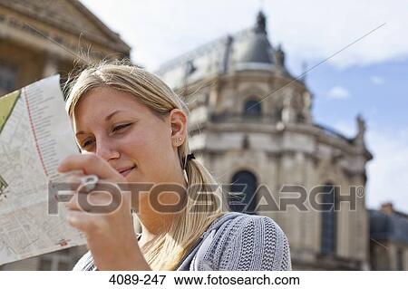 Stock Photo - Teenage girl reading a map with a palace in the background, Chateau De Versailles, Versailles, Paris, Ile-De-France, France. Fotosearch