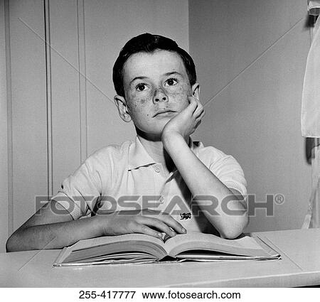 Stock Photo - Thoughtful boy sitting with open book and looking away. Fotosearch