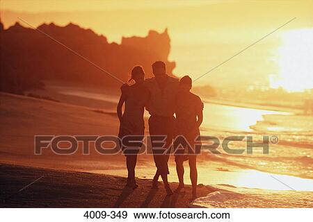 Stock Photo - Three tourists walking on the beach. Fotosearch