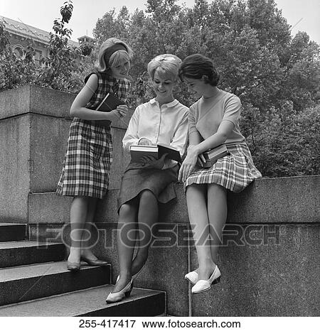Three young students checking something in book and smiling View Large Photo Image Stock Photo - Three young students checking something in book and smiling. Fotosearch