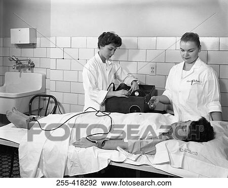 Stock Image - Two female doctors examining woman. Fotosearch