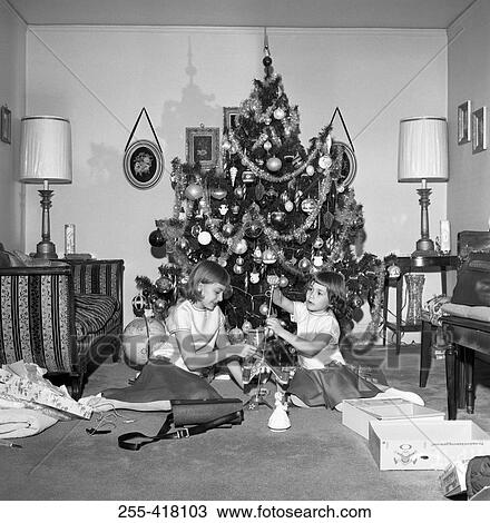 Stock Image - Two girls preparing Christmas tree. Fotosearch