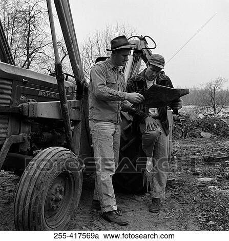 Two men standing by tractor discussing plans View Large Photo Image Stock Image - Two men standing by tractor discussing plans. Fotosearch