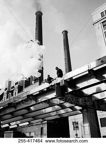 Picture - USA, New York City, low angle view of men working on roof. Fotosearch