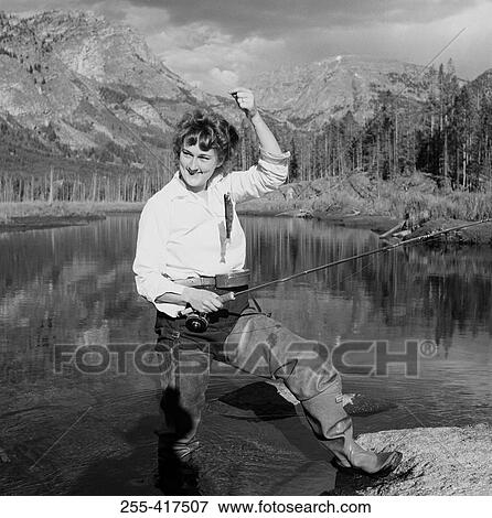 Stock Photo - Woman fly fishing in lake. Fotosearch