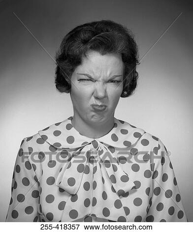 Stock Photo - Woman in spotted blouse grimacing. Fotosearch
