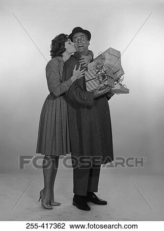 Woman kissing laughing man holding gifts, studio shot View Large Photo Image Stock Image - Woman kissing laughing man holding gifts, studio shot. Fotosearch