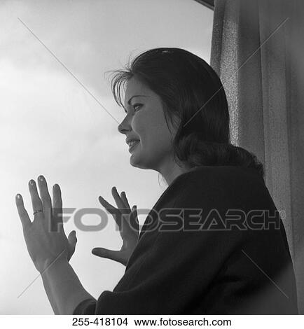 Picture - Woman looking through window. Fotosearch