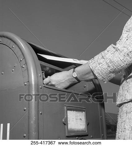 Stock Photo - Woman putting mail into mailbox, low angle view. Fotosearch