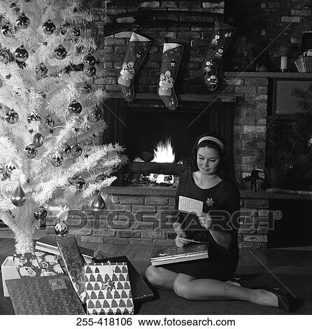 Woman reading card under Christmas tree View Large Photo Image Stock Photograph - Woman reading card under Christmas tree. Fotosearch