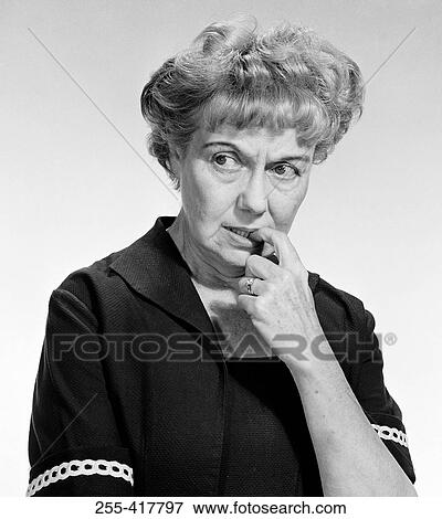 Worried mature woman biting her fingernail and looking away, studio shot View Large Photo Image Stock Photo - Worried mature woman biting her fingernail and looking away, studio shot. Fotosearch