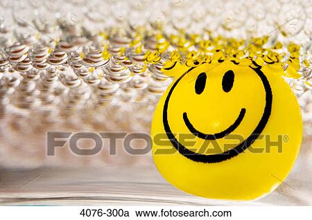 Stock Image - Yellow marble with smiley face in soap suds. Fotosearch