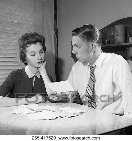 Stock Photo - Young couple checking bills at table. Fotosearch