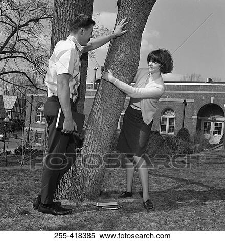 Stock Photography - Young couple flirting by tree. Fotosearch