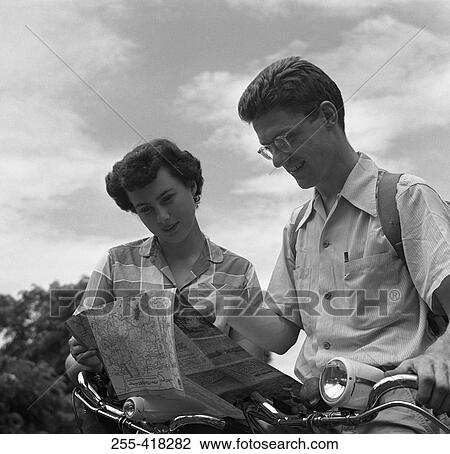 Stock Image - Young couple reading map. Fotosearch