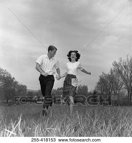 Stock Image - Young couple running through field. Fotosearch