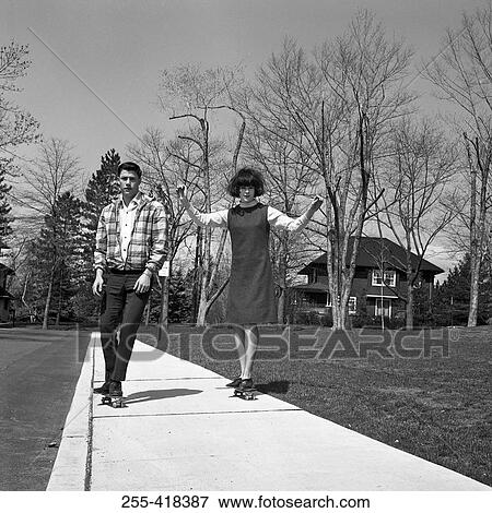 Young couple skateboarding on pavement View Large Photo Image Stock Photo - Young couple skateboarding on pavement. Fotosearch