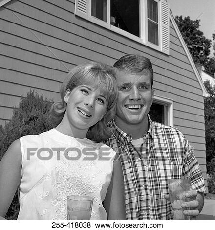 Stock Photo - Young couple standing in front of house. Fotosearch