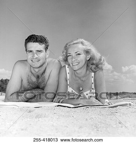 Stock Image - Young couple sunbathing on beach. Fotosearch