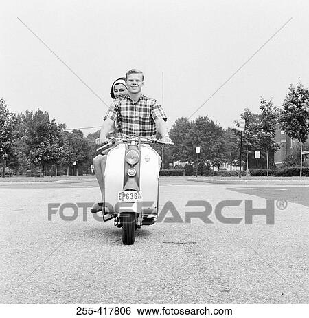 Stock Photograph - Young happy couple driving scooter. Fotosearch