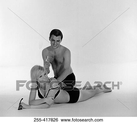 Stock Photograph - Young man applying suntan lotion on young woman's back. Fotosearch