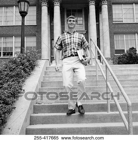 Young man carrying books on steps outside university View Large Photo Image Stock Photography - Young man carrying books on steps outside university. Fotosearch