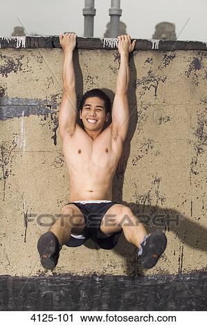 Young man hanging from a roof wall, New York City, New York State, USA View Large Photo Image Stock Image - Young man hanging from a roof wall, New York City, New York State, USA. Fotosearch