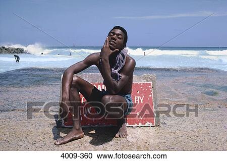 Young man sitting on the beach in front of a warning sign, Barbados View Large Photo Image Stock Image - Young man sitting on the beach in front of a warning sign, Barbados. Fotosearch