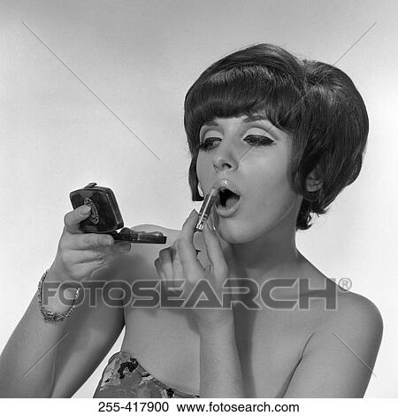 Stock Image - Young woman applying lipstick. Fotosearch