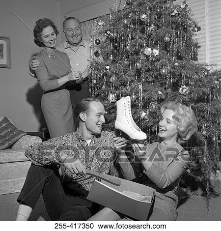 Young woman holding new ice skate, parents standing near Christmas tree View Large Photo Image Stock Image - Young woman holding new ice skate, parents standing near Christmas tree. Fotosearch