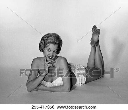 Stock Photograph - Young woman lying down and wearing bikini, studio shot. Fotosearch