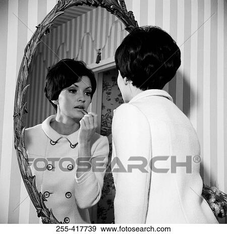 Young woman putting make-up on in front of mirror View Large Photo Image Stock Photo - Young woman putting make-up on in front of mirror. Fotosearch