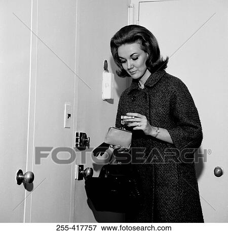 Stock Photo - Young woman putting money into purse before leaving house. Fotosearch
