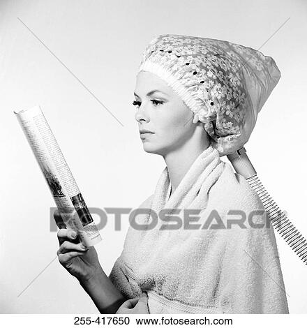Stock Image - Young woman reading magazine at hair salon. Fotosearch