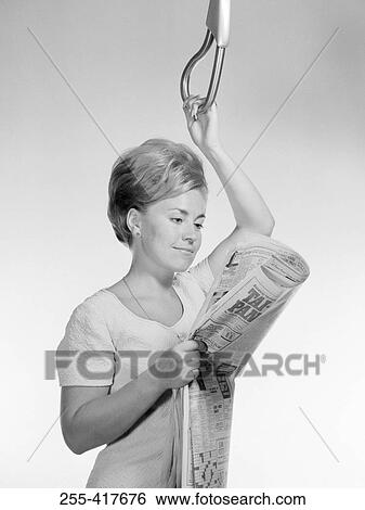 Young woman reading newspaper while holding handle View Large Photo Image Stock Photograph - Young woman reading newspaper while holding handle. Fotosearch