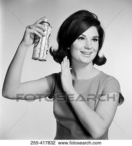 Stock Image - Young woman using hairspray. Fotosearch