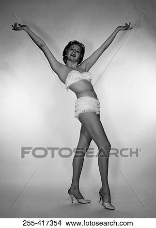 Young woman wearing bikini with raised hands, studio shot View Large Photo Image Picture - Young woman wearing bikini with raised hands, studio shot. Fotosearch