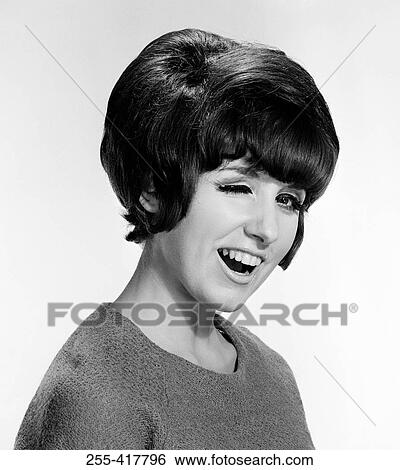 Stock Photograph - Young woman winking, studio shot. Fotosearch