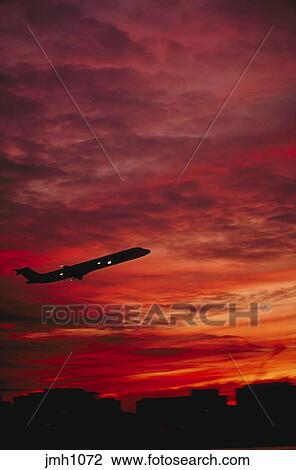 Commercial Jet Airliner In Flight Shortly After Takeoff From Washington National Airport Full Silhouette Side View Against Colorful Early Evening Sky Shows Local Skyline At Bottom Transportation Aviation Travel Stock Image