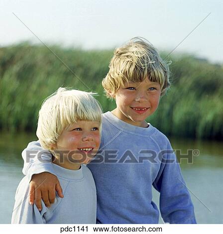 Portrait Of Two Young Boys With Blond Hair Smiling While Sitting