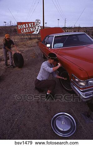 Two women changing a flat tire on a classic red cadillac near Reno, NV