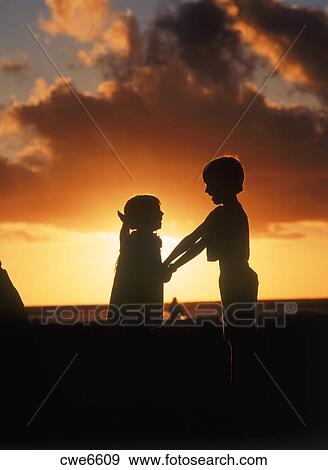 Boy And Girl Holding Hands On Beach At Sunset Stock Photo Cwe6609 Fotosearch