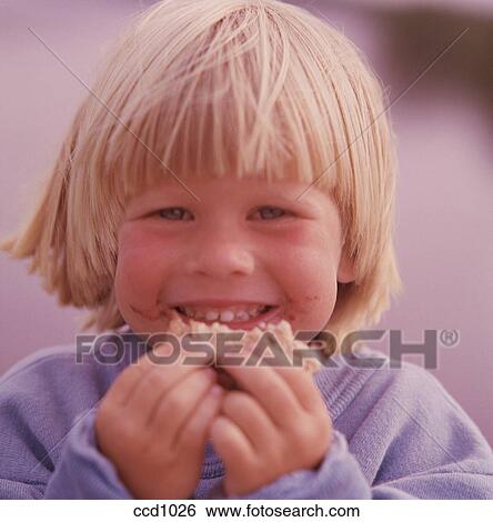Close Up Of A Blonde Hair Blue Eyed Boy Eating Hand Food Stock