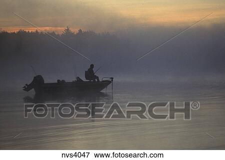 Silhouette Of A Bass Angler On Hi S Boat Fishing At Sunrise Stock