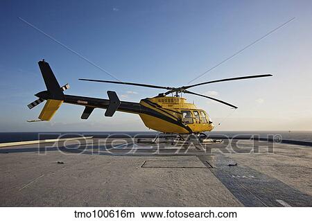 A Bell 407 utility helicopter on the helipad of an oil rig. View Large Photo Image Picture - A Bell 407 utility helicopter on the helipad of an oil rig.. Fotosearch