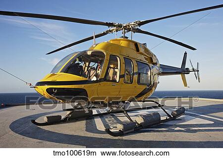 A Bell 407 utility helicopter on the helipad of an oil rig. View Large Photo Image Picture - A Bell 407 utility helicopter on the helipad of an oil rig.. Fotosearch